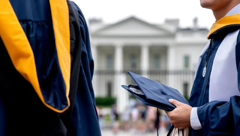 FILE IMAGE - Students from George Washington University wear their graduation gowns outside of the White House in Washington, D.C., on May 18, 2022. (Photo by STEFANI REYNOLDS/AFP via Getty Images)
